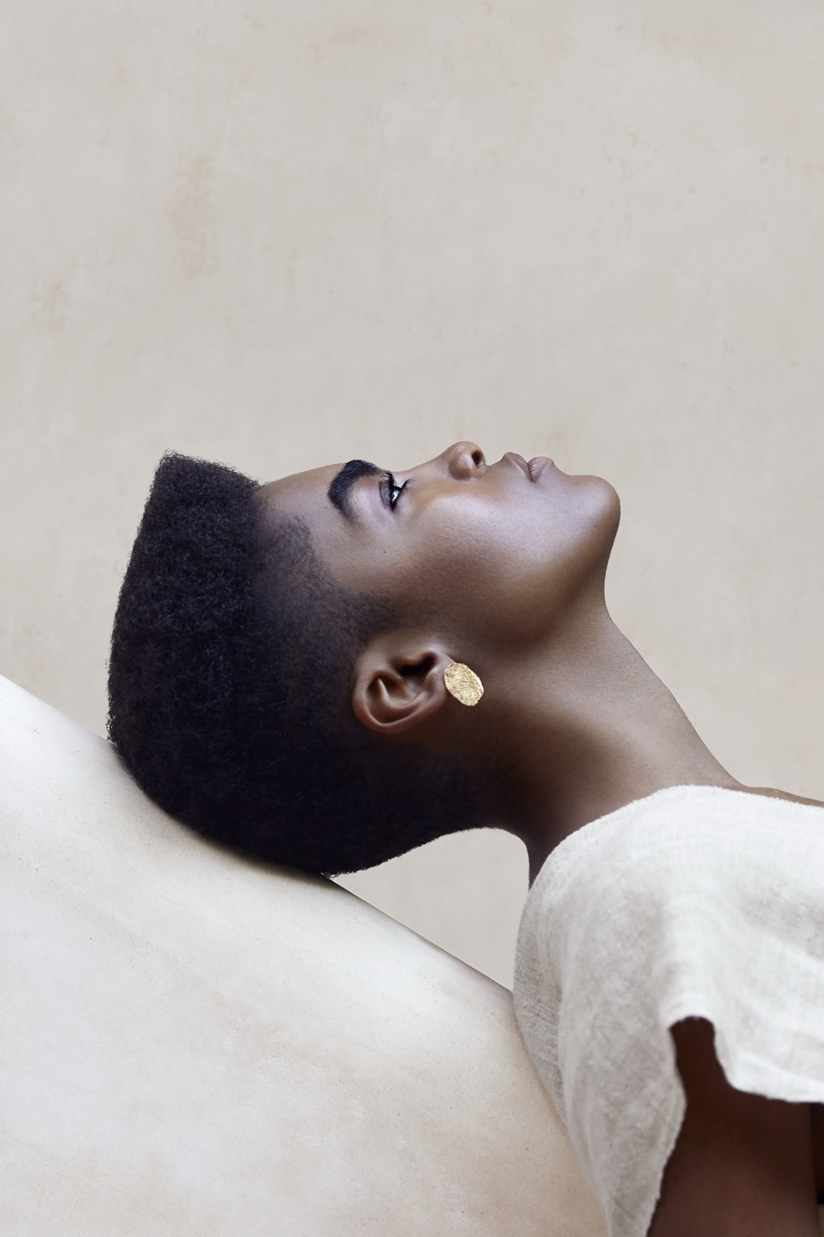 Beauty portrait in profile, cream tones and gold ear piece