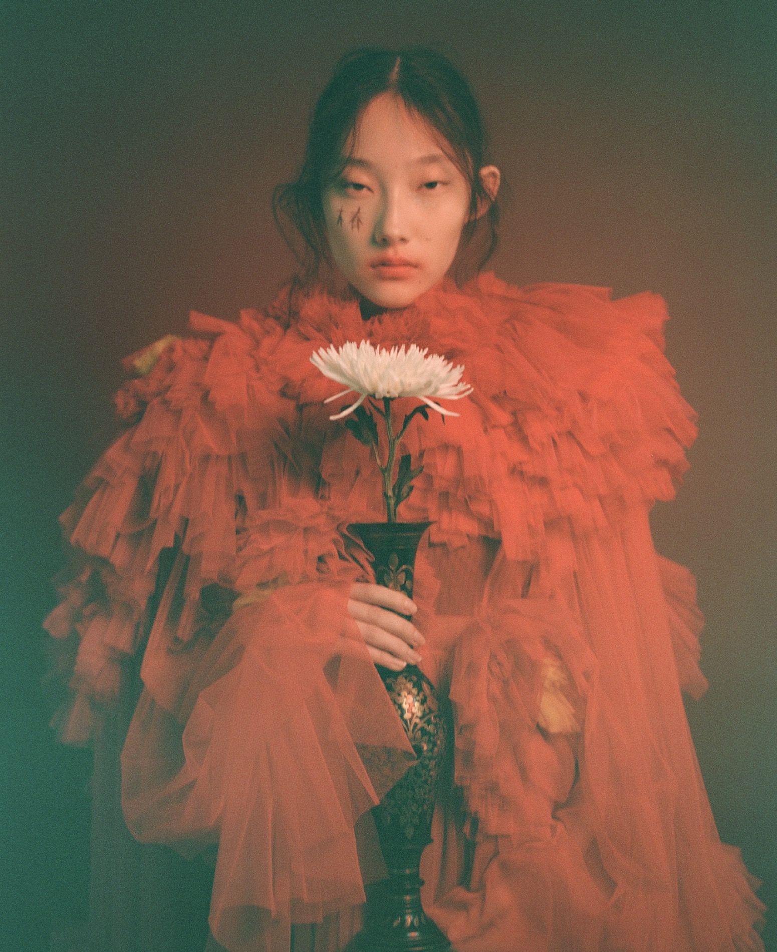 Editorial hair and make-up, model in voluminous red tulle holding a white flower