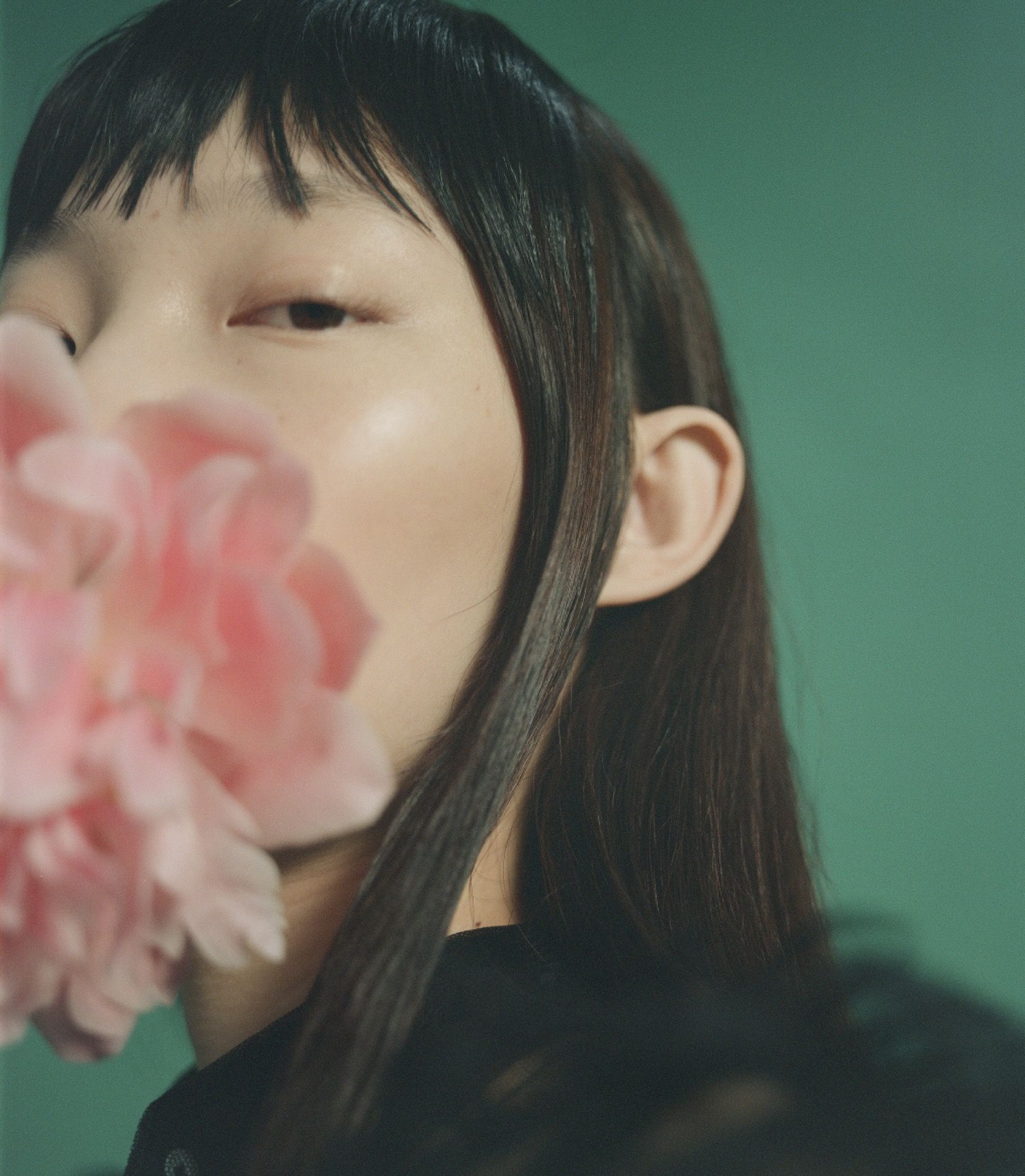 Beauty editorial, half face against teal with a pink peony